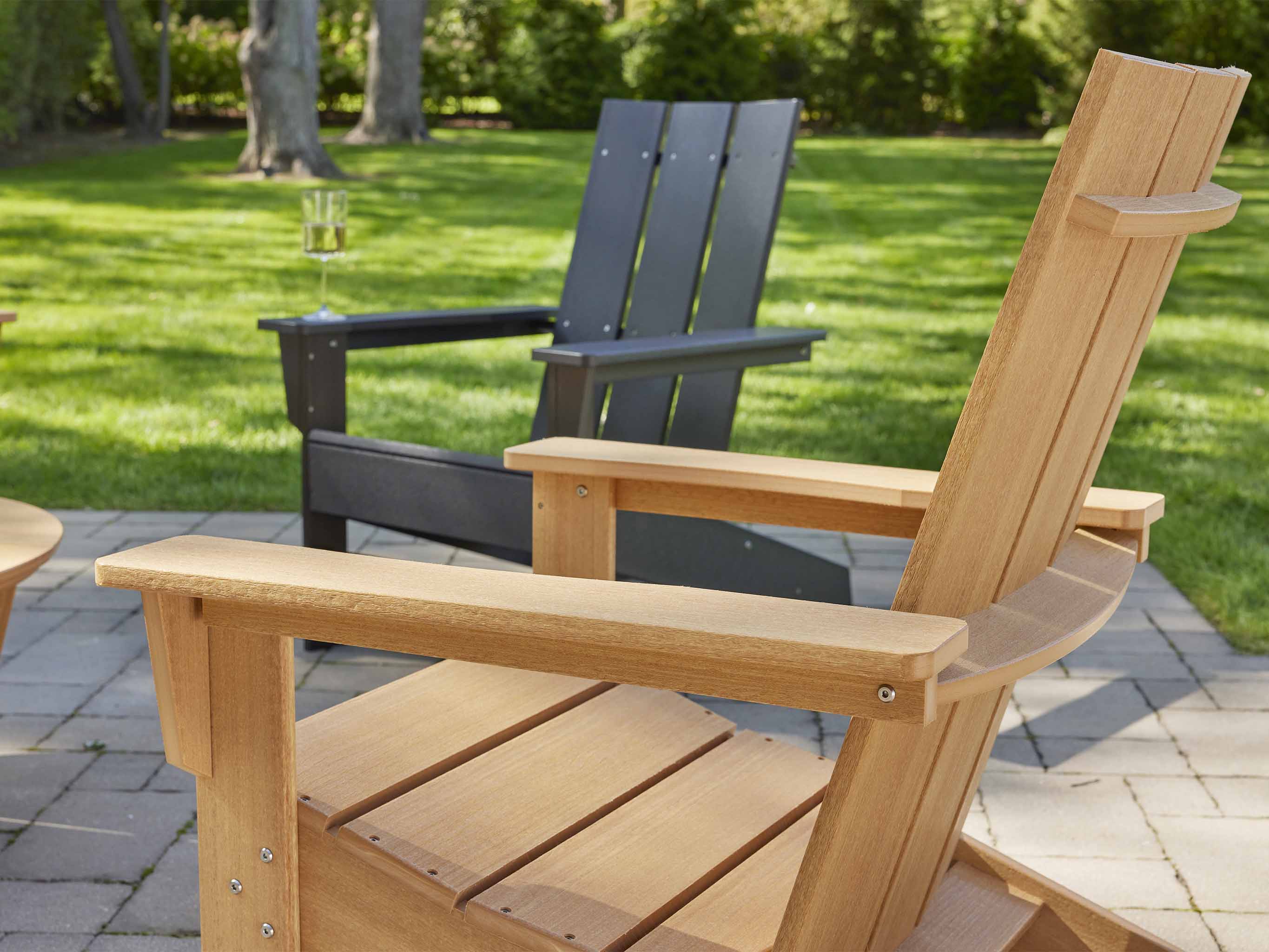 Aria Adirondack Chairs Natural Teak and Black on Stone Patio
