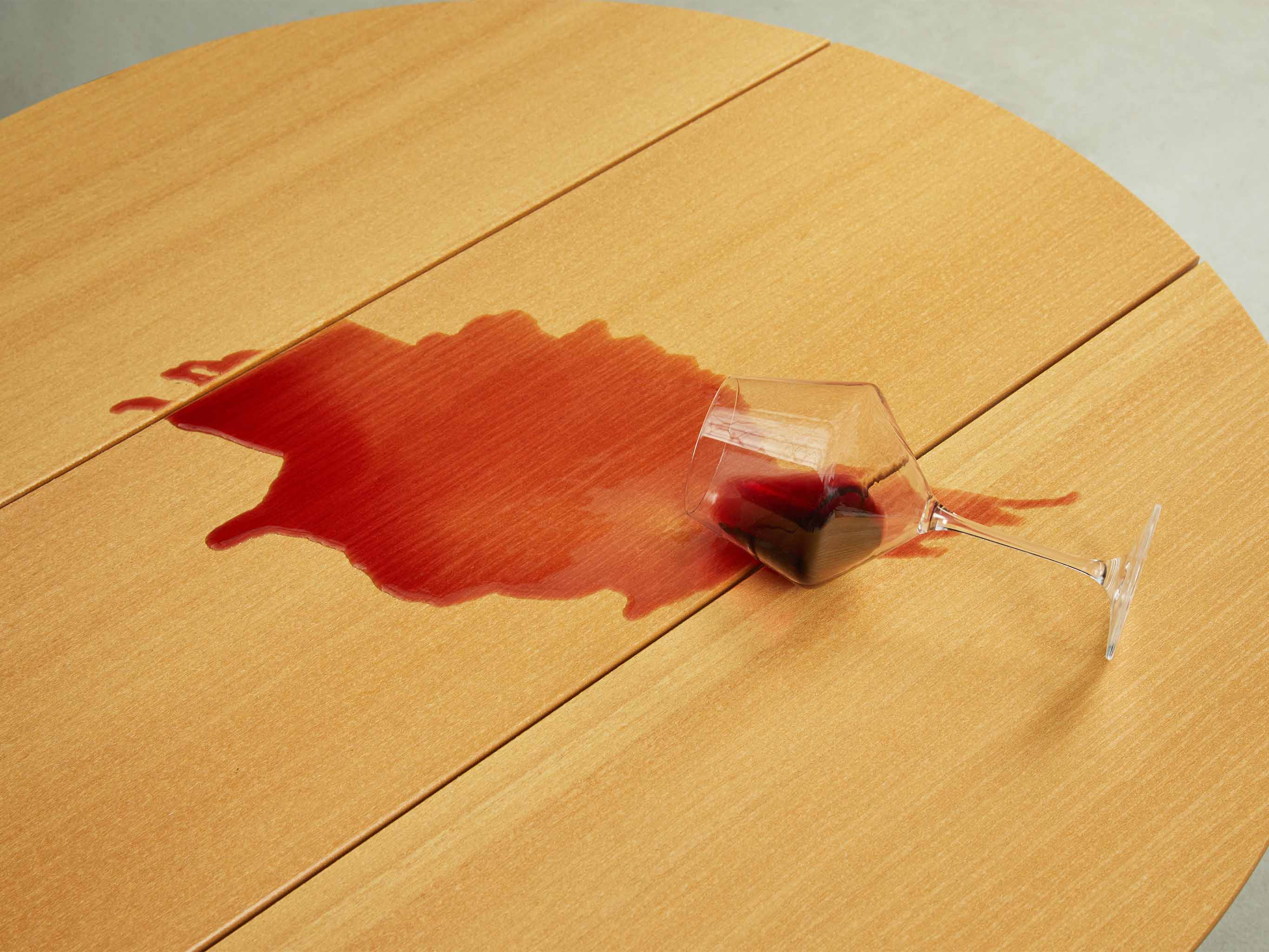 Red wine spilled onto a table top with glass on its side