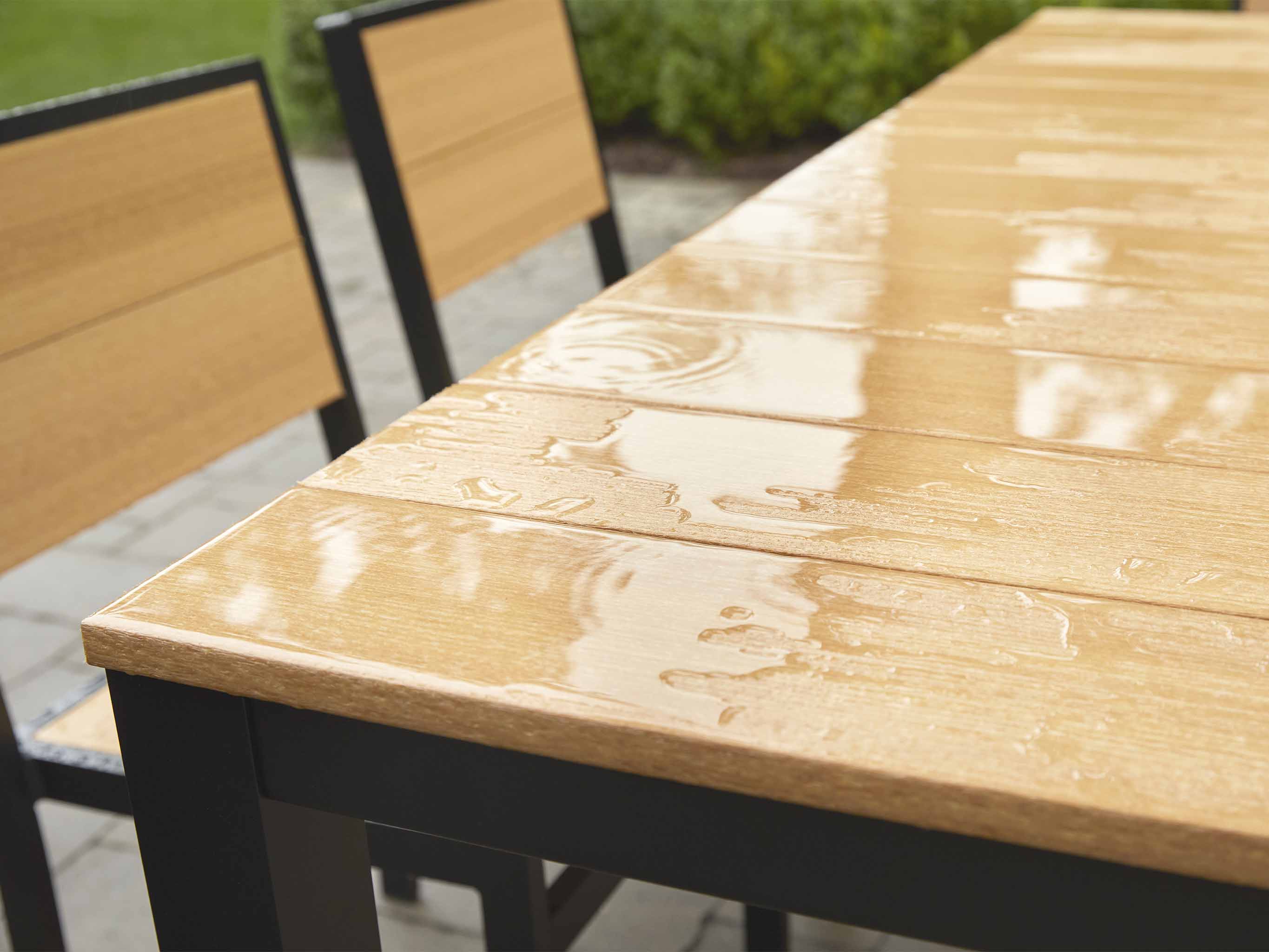 Park City Dining Table in the rain black frame natural teak on brick patio