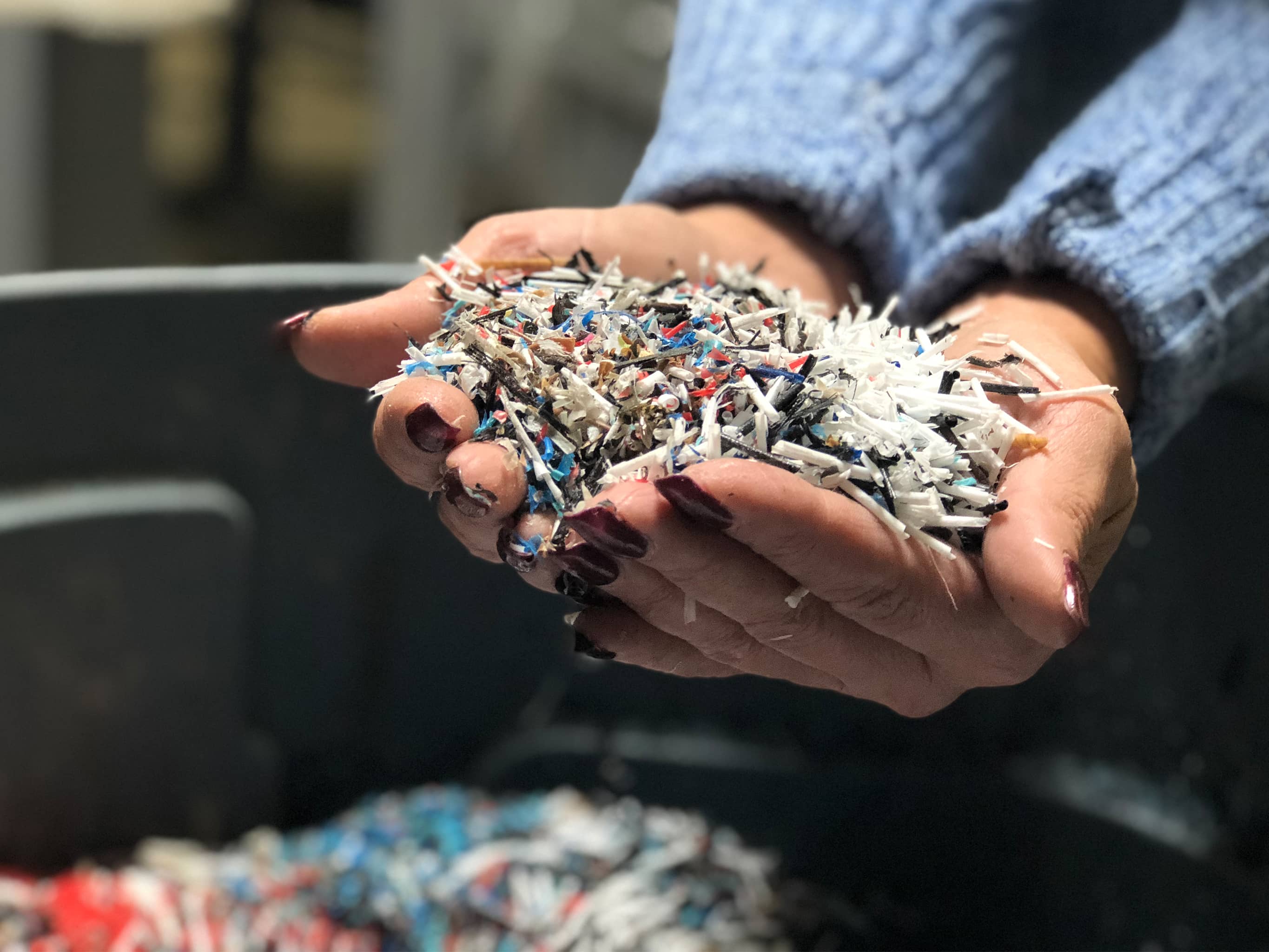 Hands holding shredded recycled HDPE plastic 